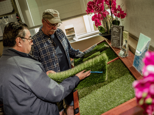 Two contractors are looking at premium turf samples in the North Phoenix showroom at The Synthetic Grass Store